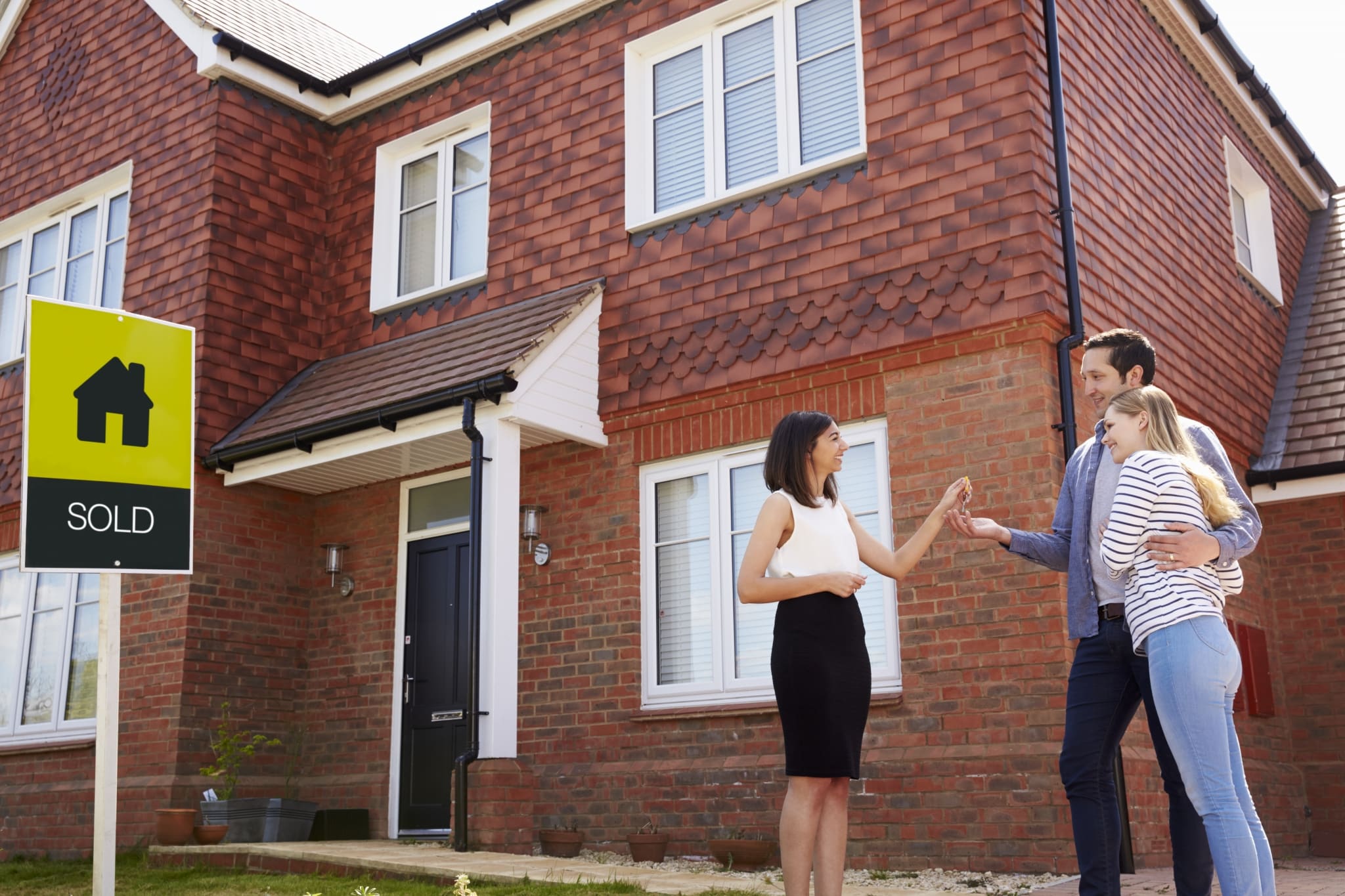 Young Couple Collecting Keys To New Home From Realtor