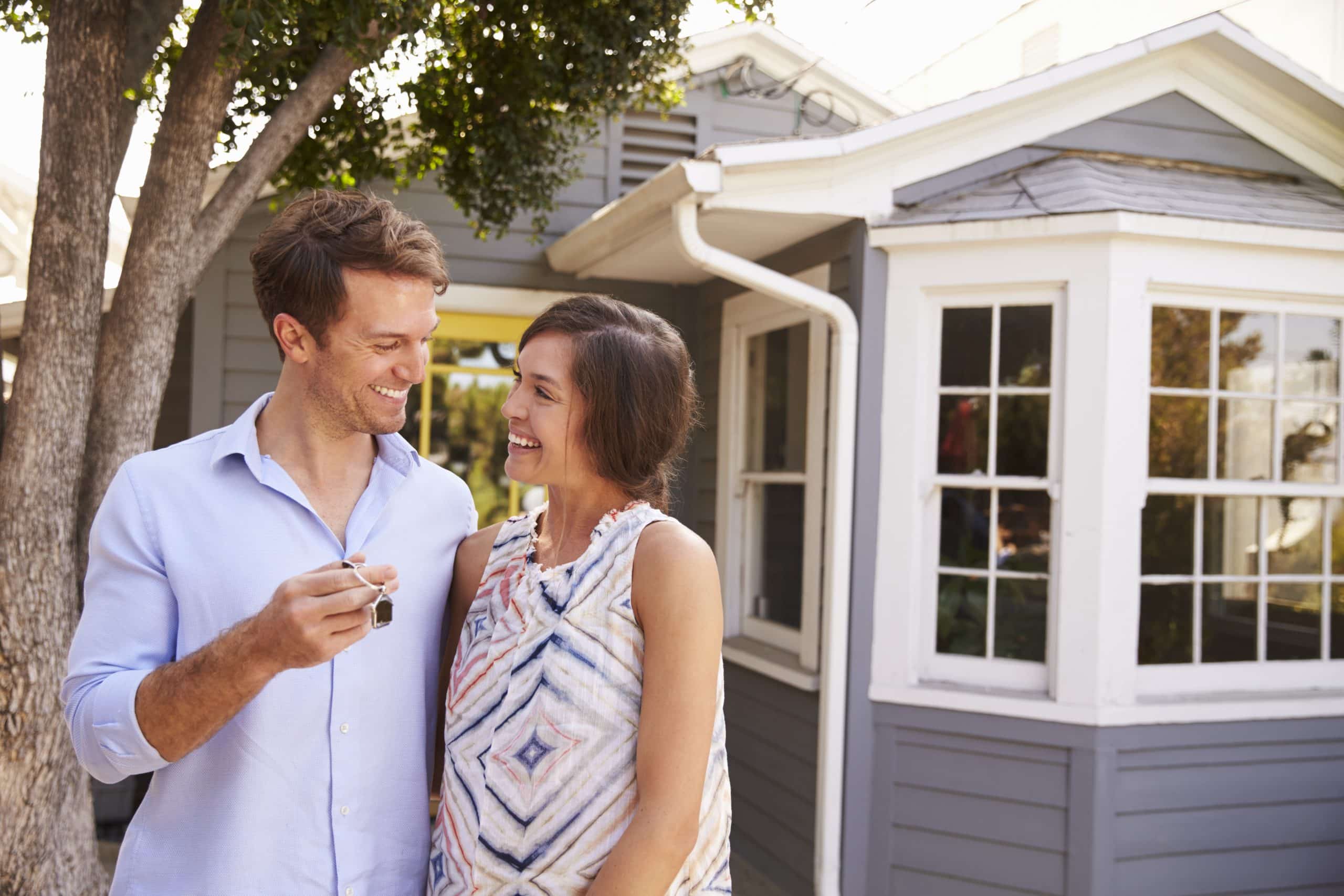 Couple With Keys Standing Outside New Home